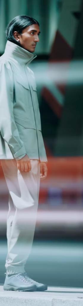 A man looking off to the side in a futuristic Arc-teryx Veilance grey jacket with matching pants and shoes