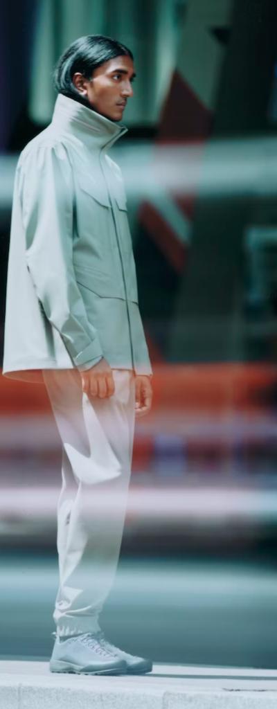A man looking off to the side in a futuristic Arc-teryx Veilance grey jacket with matching pants and shoes
