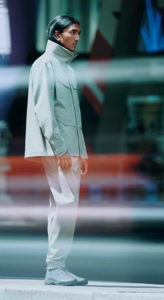 A man looking off to the side in a futuristic Arc-teryx Veilance grey jacket with matching pants and shoes