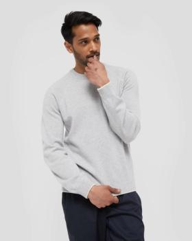 A man wearing a grey WANT Les Essentiels sweater and navy blue pants