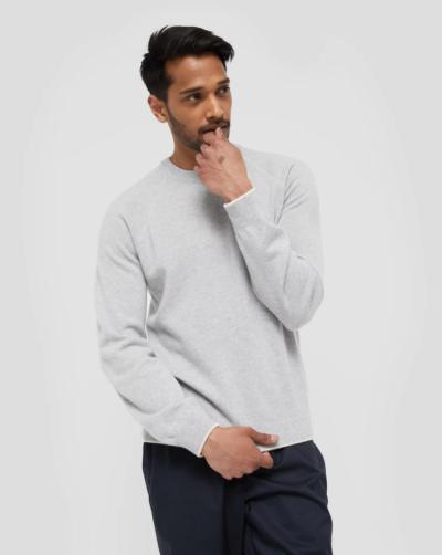 A man wearing a grey WANT Les Essentiels sweater and navy blue pants
