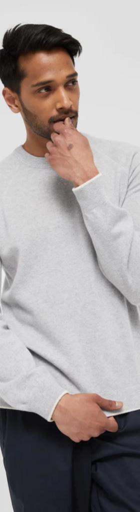 A man wearing a grey WANT Les Essentiels sweater and navy blue pants