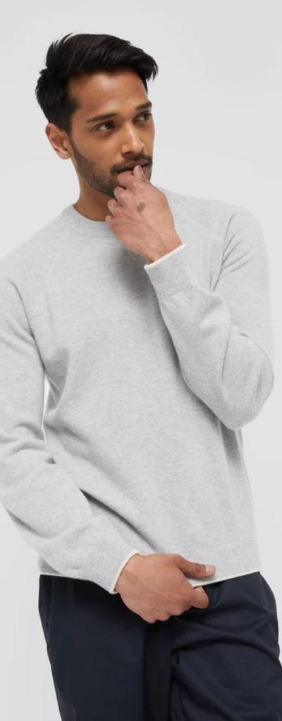 A man wearing a grey WANT Les Essentiels sweater and navy blue pants
