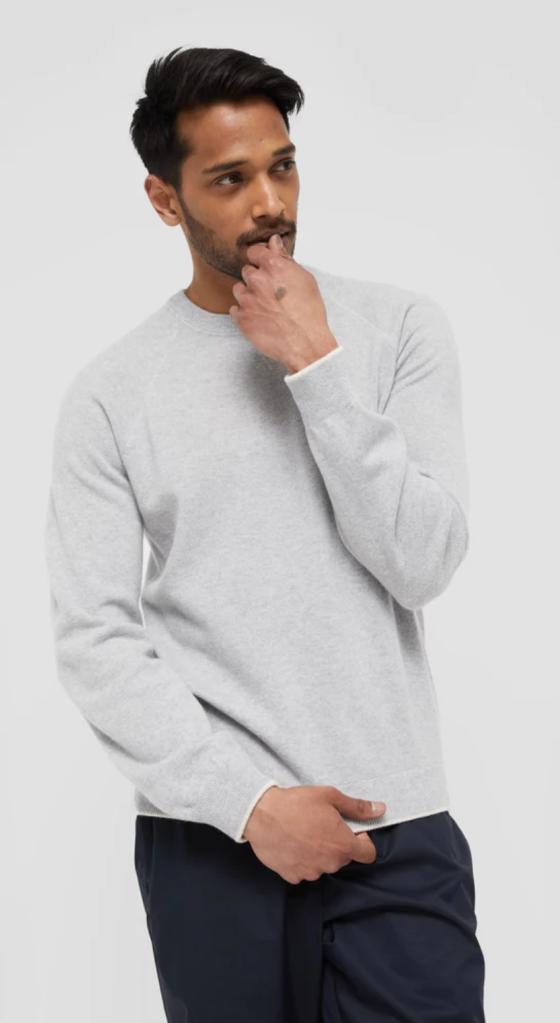 A man wearing a grey WANT Les Essentiels sweater and navy blue pants