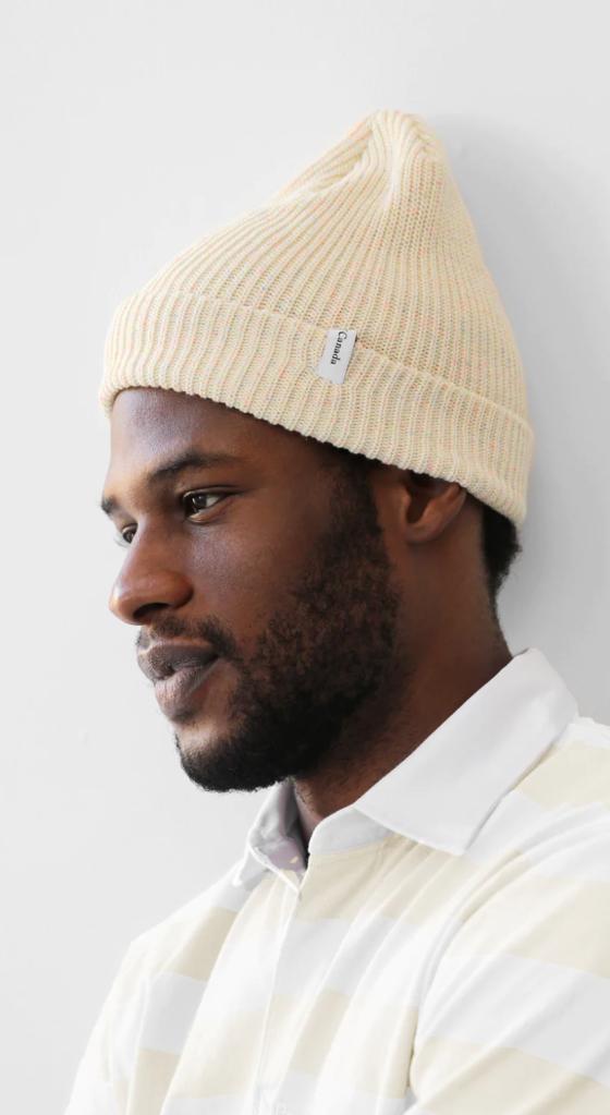 A close up of a man wearing a off whire Province of Canada button up shirt and beanie
