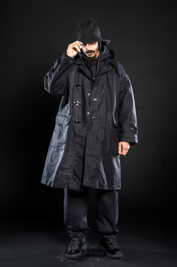 A man wearing all black including an Engineered Garments jacket, bucket hat, and pants.