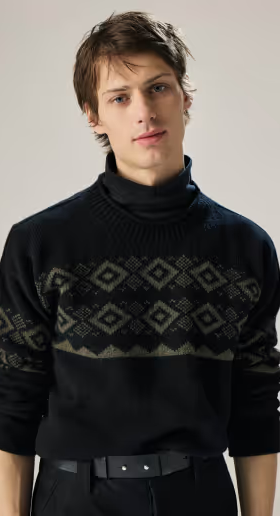 A man wearing a navy blue turtleneck sweatshirt with the sleeves rolled up