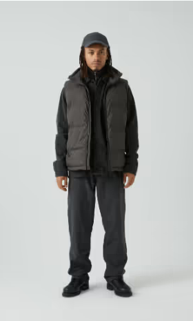 A man with dreads wearing a grey puffy Mads Norgaard vest and a matching hoodie, pants and hat.
