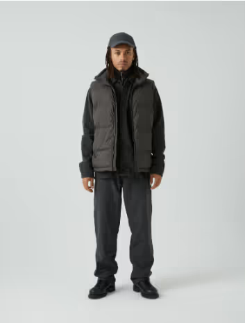 A man with dreads wearing a grey puffy Mads Norgaard vest and a matching hoodie, pants and hat.
