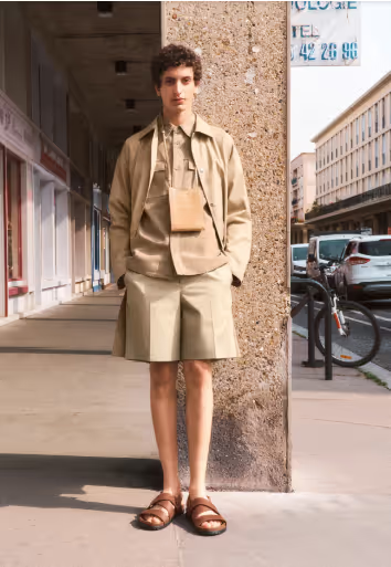 A man wearing a brown A.P.C. outfit which includes shorts, a short-sleeve button up under a long-sleeve button up and a bag