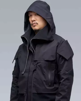 A man wearing a black Acronym jacket with his hood on