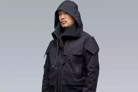 A man wearing a black Acronym jacket with his hood on