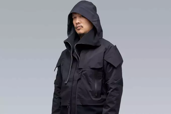 A man wearing a black Acronym jacket with his hood on