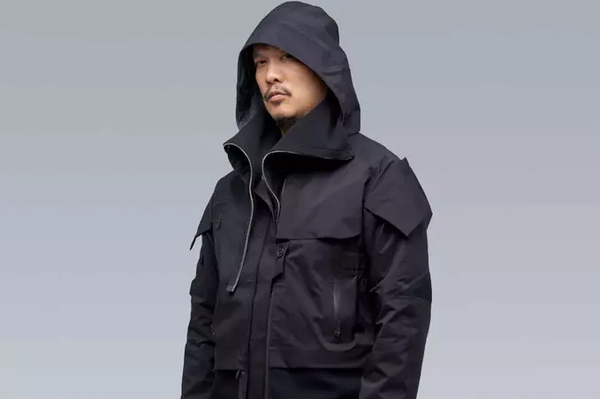 A man wearing a black Acronym jacket with his hood on