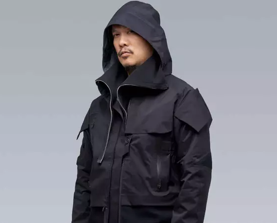 A man wearing a black Acronym jacket with his hood on