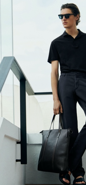 A young man with slicked back hair wearing a short-sleeve Massimo Dutti shirt, dress pants and a matching leather bag