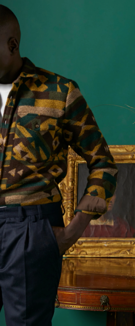 A man wearing a orange and brown Portuguese Flannel tucked into navy blue pants