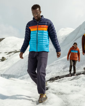 A group of people hiking on a snowy mountain wearing colorful CotoPaxi Puffy Jackets and active wear