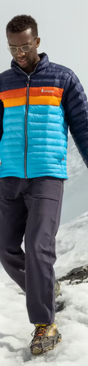 A group of people hiking on a snowy mountain wearing colorful CotoPaxi Puffy Jackets and active wear