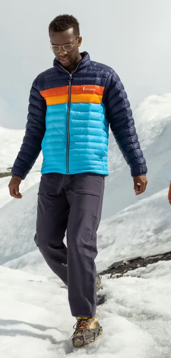 A group of people hiking on a snowy mountain wearing colorful CotoPaxi Puffy Jackets and active wear