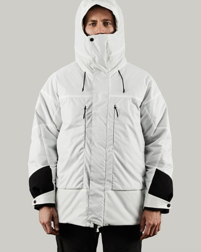 A man in a photoshoot setting wearing a white futuristic looking Vollebak Jacket