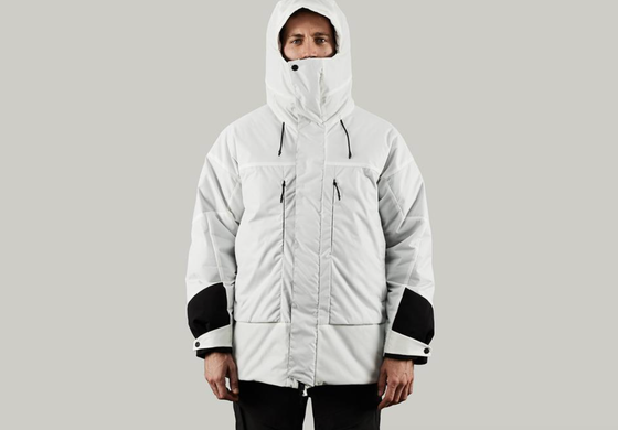 A man in a photoshoot setting wearing a white futuristic looking Vollebak Jacket