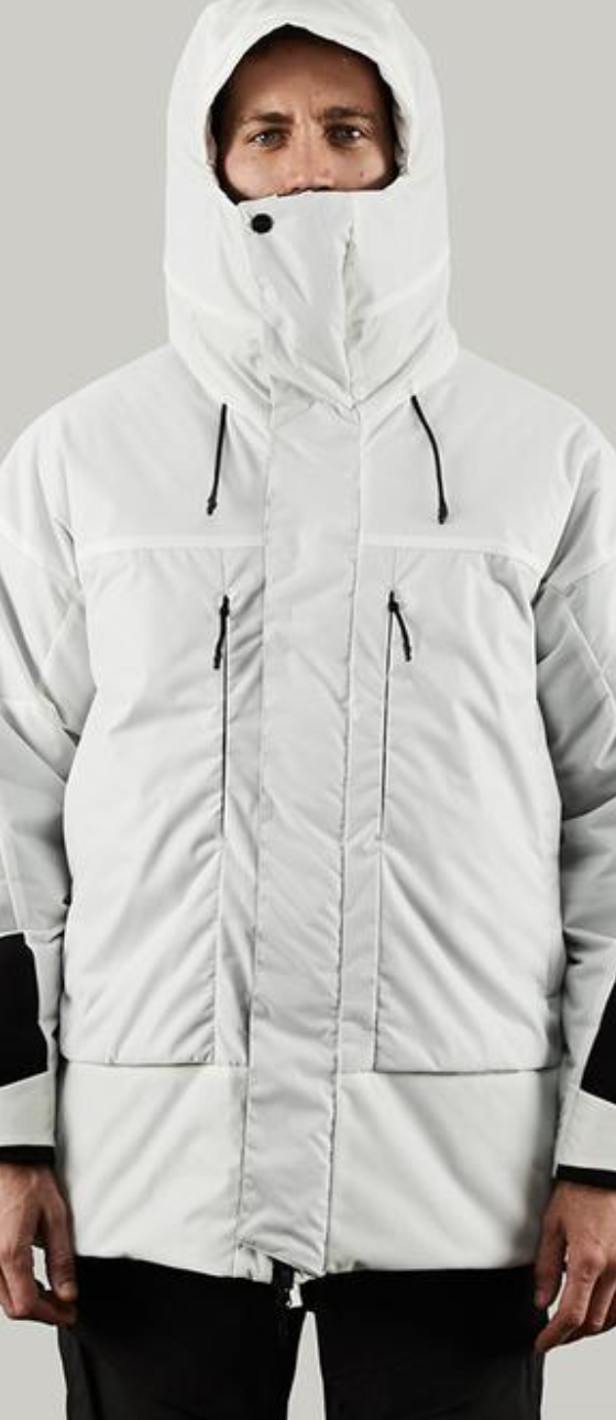 A man in a photoshoot setting wearing a white futuristic looking Vollebak Jacket