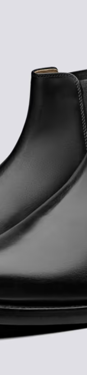 A black pair of Grenson boots that are similar to Blundstones on a white background
