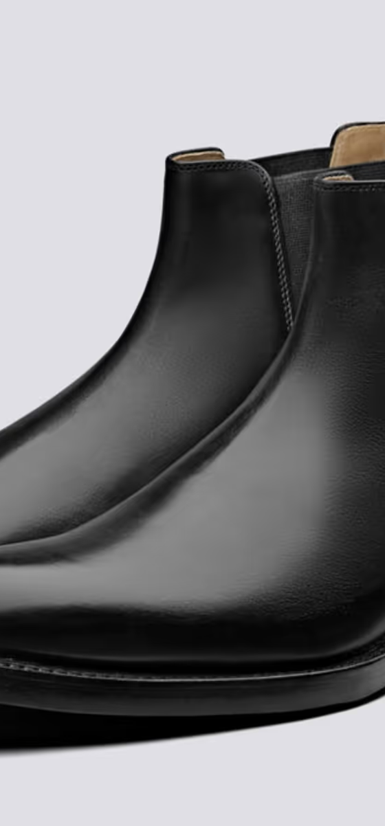 A black pair of Grenson boots that are similar to Blundstones on a white background