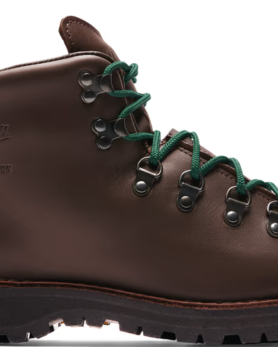 A brown pair of Danner boots with Green laces on a white background