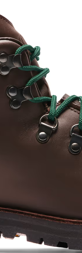 A brown pair of Danner boots with Green laces on a white background