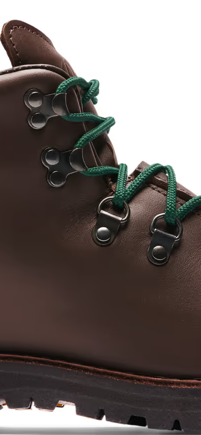 A brown pair of Danner boots with Green laces on a white background