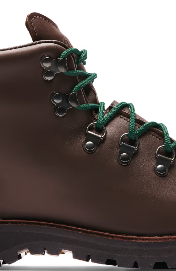 A brown pair of Danner boots with Green laces on a white background