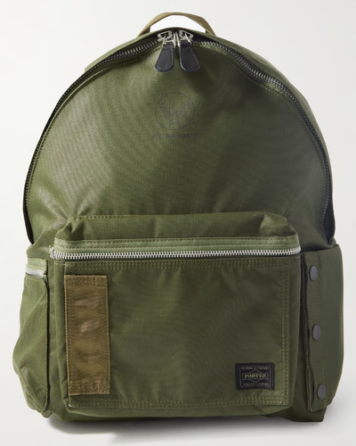 A dark green Porter Yoshida backpack with a silver zipper on a white background