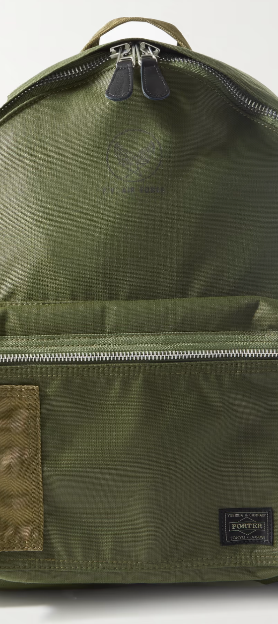 A dark green Porter Yoshida backpack with a silver zipper on a white background