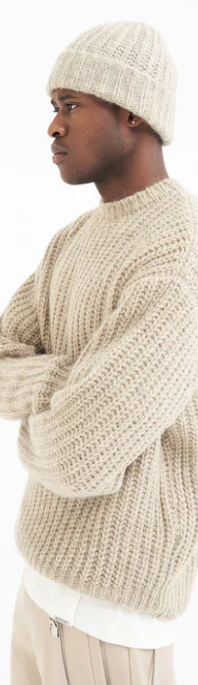 A man wearing a Represent beige knit sweater with a matching beanie and pants