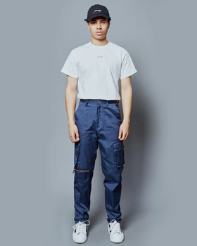A man wearing a Public School NYC white logo t-shirt and navy blue hat and pants along with white sneakers