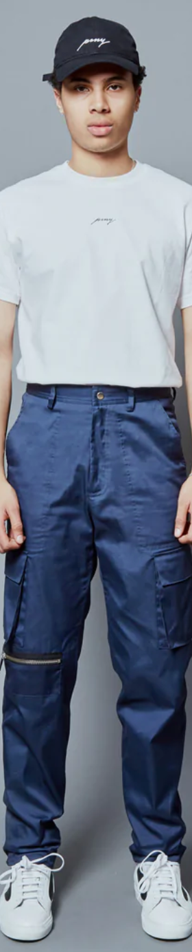 A man wearing a Public School NYC white logo t-shirt and navy blue hat and pants along with white sneakers