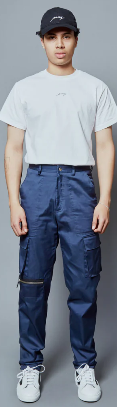 A man wearing a Public School NYC white logo t-shirt and navy blue hat and pants along with white sneakers
