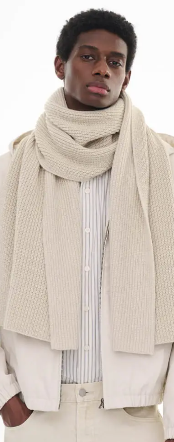 A man wearing an oversize Uniqlo beige scarf with a striped button up and a beige coat