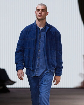 A man walking in a Bassike denim jacket with matching button up and pants
