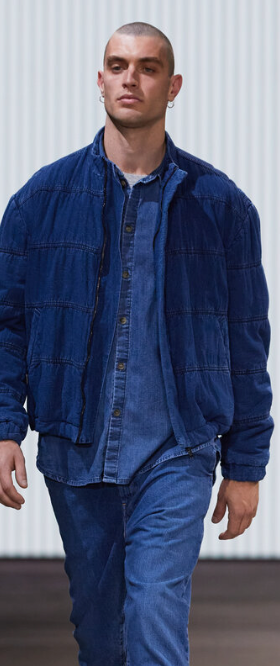 A man walking in a Bassike denim jacket with matching button up and pants