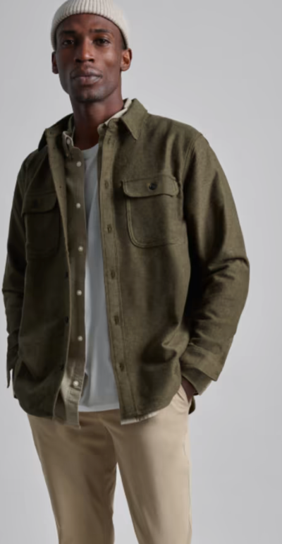 A man wearing a Olive Everlane overshirt, a white beanie and khaki pants