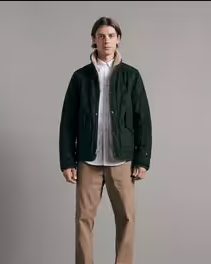 A man wearing a green Rag & Bone jacket along with a white button up and khaki pants