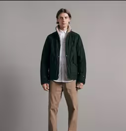 A man wearing a green Rag & Bone jacket along with a white button up and khaki pants