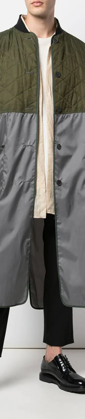 A man wearing a green Haider Ackermann trench coat with black pants and shoes