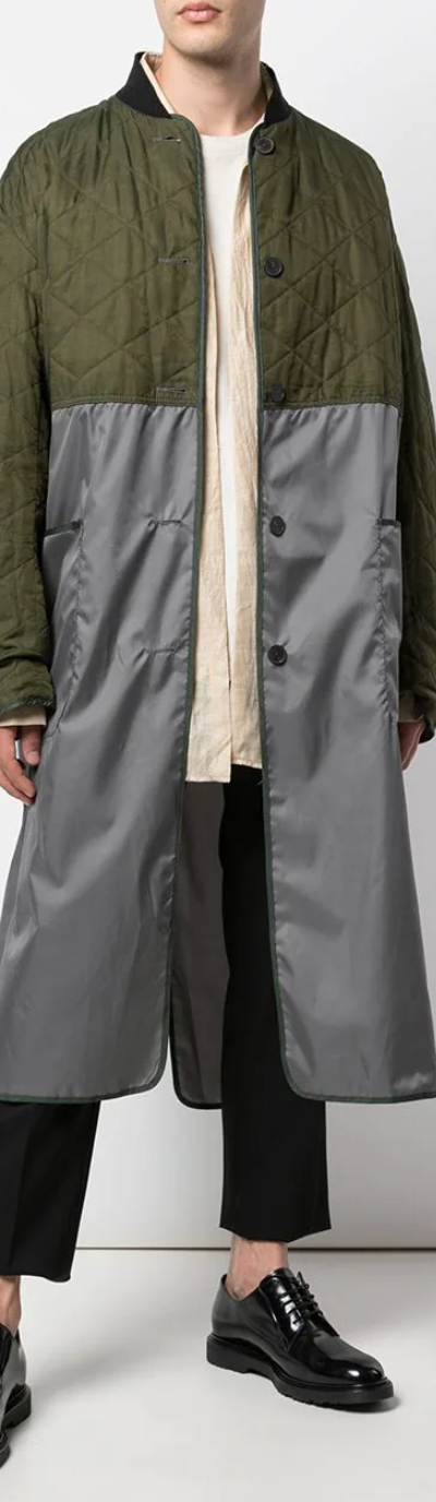 A man wearing a green Haider Ackermann trench coat with black pants and shoes