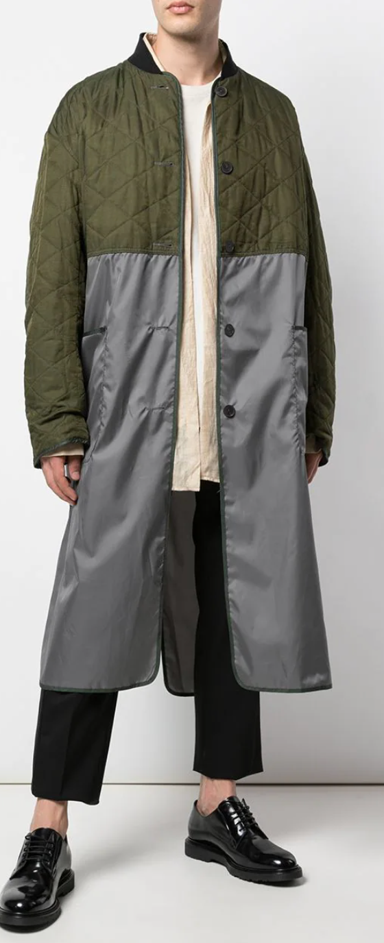 A man wearing a green Haider Ackermann trench coat with black pants and shoes