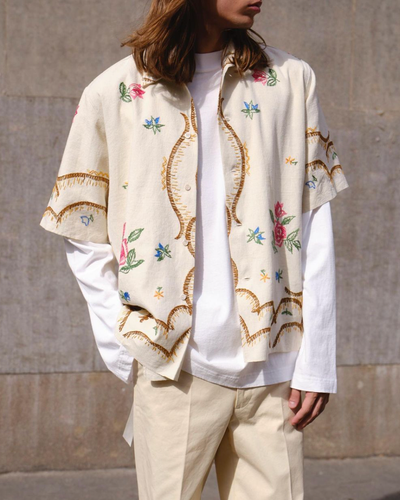 A man with long hair wearing a Damir Doma beige floral button up with biege pants and a white longsleeve