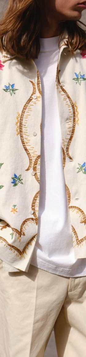 A man with long hair wearing a Damir Doma beige floral button up with biege pants and a white longsleeve